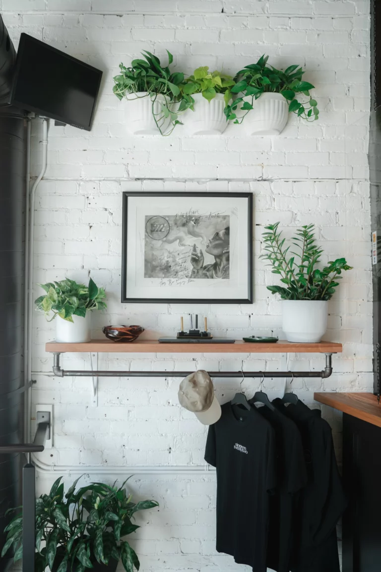 Original 1922 store photograph with framed artwork, hanging plants, and branded merchandise
