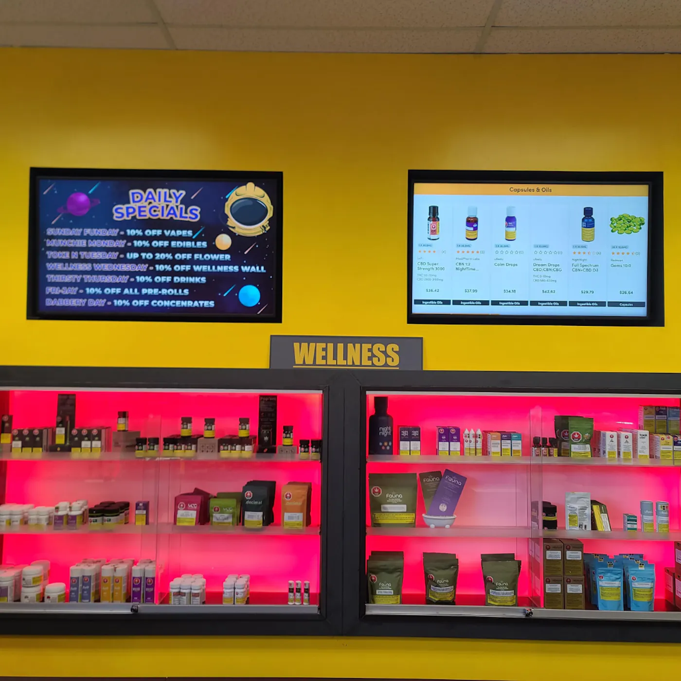Take Off Cannabis wellness display and daily-specials screen against a yellow wall